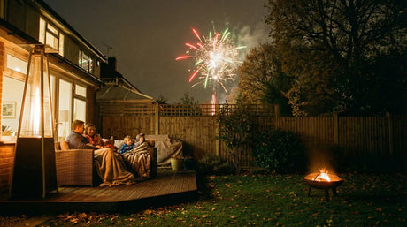 Family watching a garden firework display from their patio on Bonfire Night in a British back garden