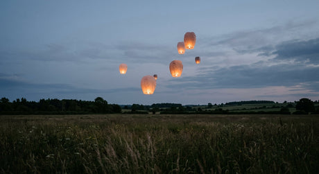 Lit sky lanterns drifting up into a dark night sky