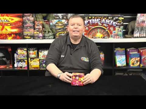 Man presenting Angel Dust 20-shot cake by Brothers Pyrotechnics in a fireworks store, highlighting its use for family-friendly celebrations.