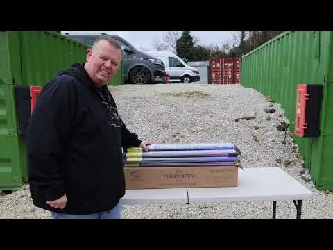a man standing next to a table with boxes of fireworks on it
