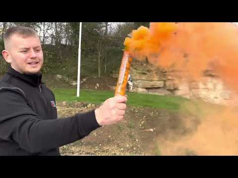 Galactic Fireworks team member demonstrating the wire pull ignition on the orange smoke grenade.