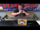 Presenter showcasing the Heavy Hitter Cake by Primed Pyrotechnics on a review bench, highlighting its features for party and celebration fireworks.