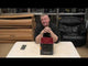 Presenter showcasing Electron 36-shot cake firework by Evolution Fireworks on a table, highlighting its compact design and performance.
