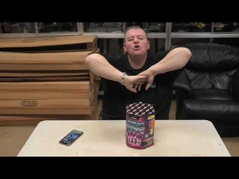 Demonstration of Long Shot 19-Shot Cake by Primed Pyrotechnics, with presenter showcasing the firework on a table before use.