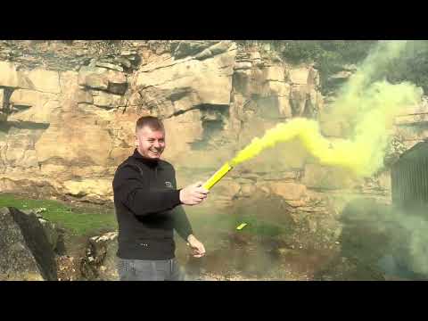Man using Yellow Handheld Smoke Grenade by Cube Fireworks outdoors, releasing dense yellow smoke for over 90 seconds.