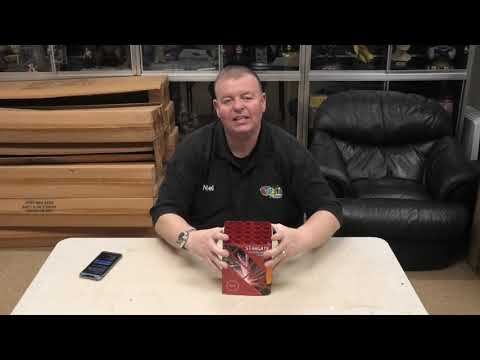 Presenter showcasing Stargate 25-Shot Cake by Evolution Fireworks on a table, highlighting features for Galactic Fireworks product demo.