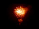 Burst from Gladiator 50-shot fanned cake showing a vivid orange explosion in the night sky, perfect for high-impact fireworks shows.