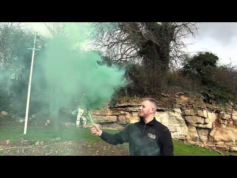 Man holding active Green Handheld Smoke Grenade by Cube Fireworks emitting dense green smoke, ideal for photoshoots and special events.